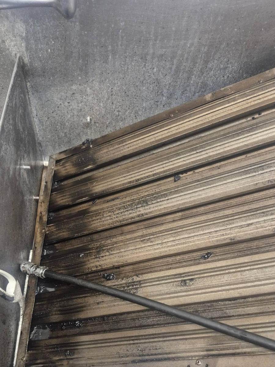 Filtres à graisse d'une hotte de cuisine commerciale encrassés de graisse carbonisée, pendant le dégraissage à la lance